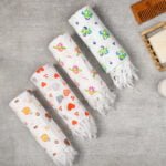 Floral Giza Cotton Bath Towels – Rolled Set with Soap & Comb Four floral bath towels in assorted prints rolled neatly, placed side by side with a soap and wooden comb in a lifestyle setting.